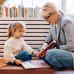 Ett förskolebarn och en pedagog bläddrar i en bok tillsammans | © miniseries / Getty Images