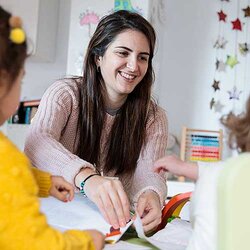 Glad förskollärare tillsammans med barn i förskolan | © Lourdes Balduque / Getty Images