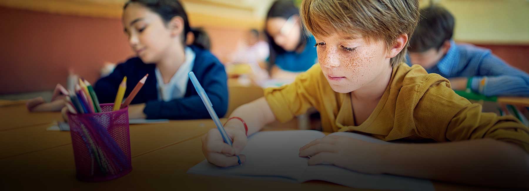 Pojke i närbild - mellanstadieelever skriver för hand i sitt klassrum - konferensen Läs- och skrivundervisning