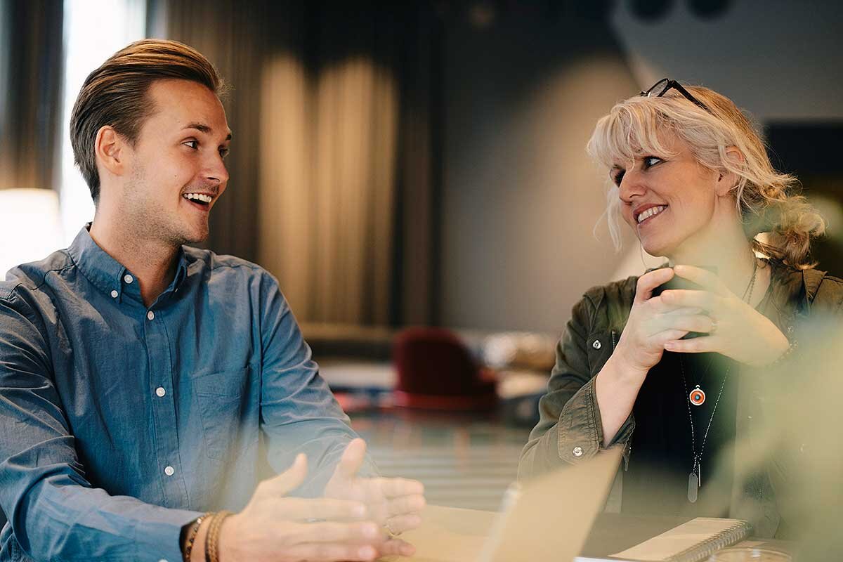En man och en kvinna i trevligt samtal i kontorsmiljö | © Maskot / Getty Images